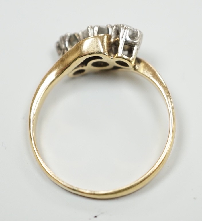 A yellow metal and three stone diamond set crossover ring, size K, gross weight 2.1 grams